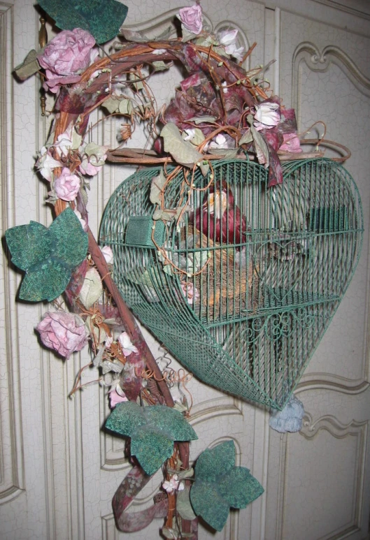 a heart - shaped birdcage and pink flowers are on a vintage wall