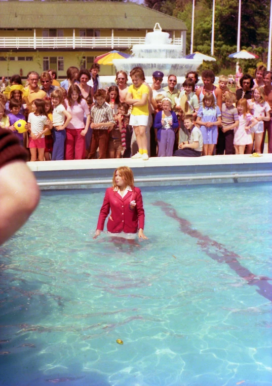 a child in a red suit is playing with a frisbee near people