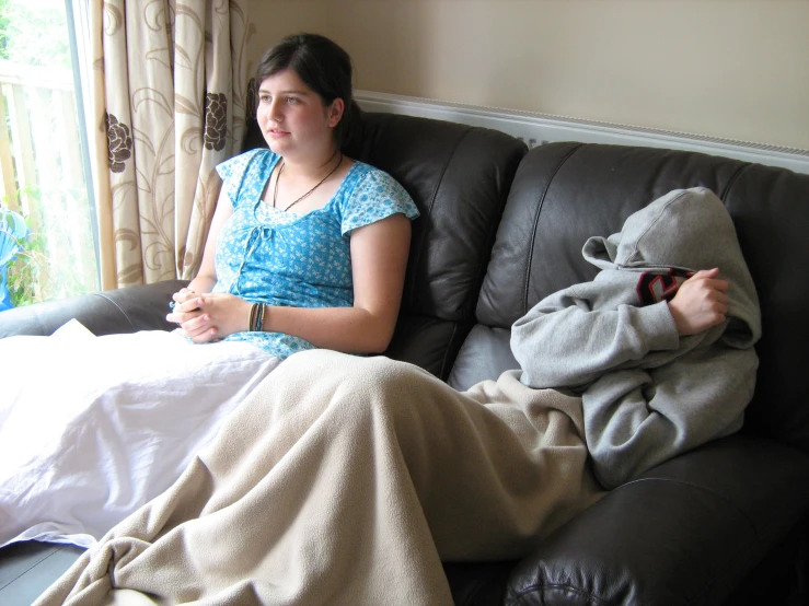 a girl sitting on a couch with a blanket around her