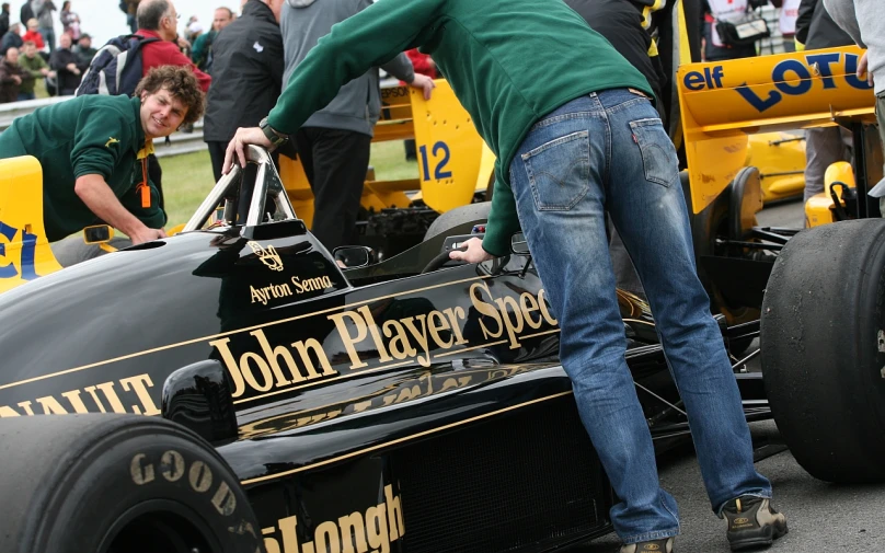 people watching a person hing around an old race car