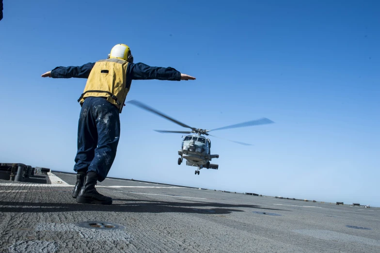 man in yellow jacket next to a black helicopter