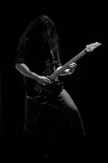 a black and white image of a person playing guitar