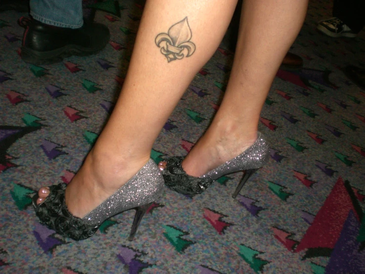 a woman with a tattoo on her legs, showing off her glitter shoes