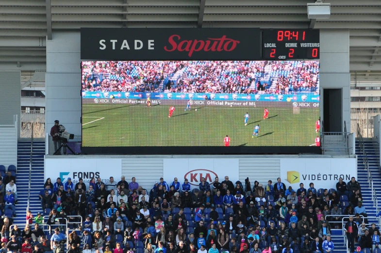 fans are watching an electronic scoreboard at a stadium