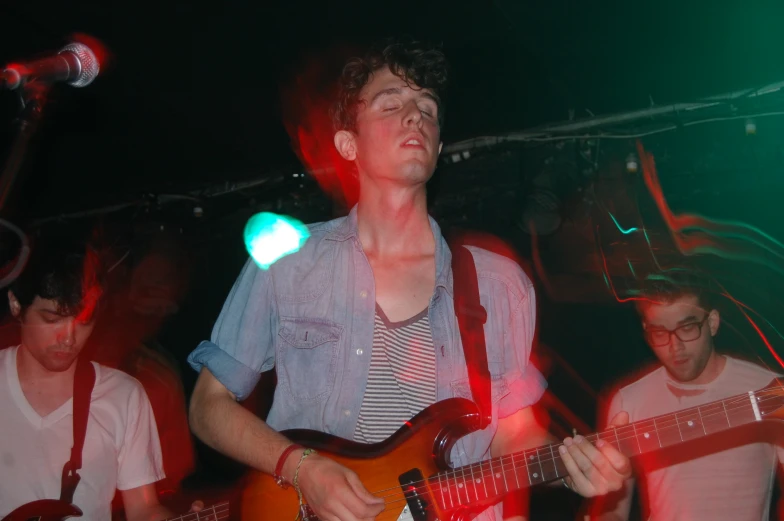 a man playing guitar with other men in the background