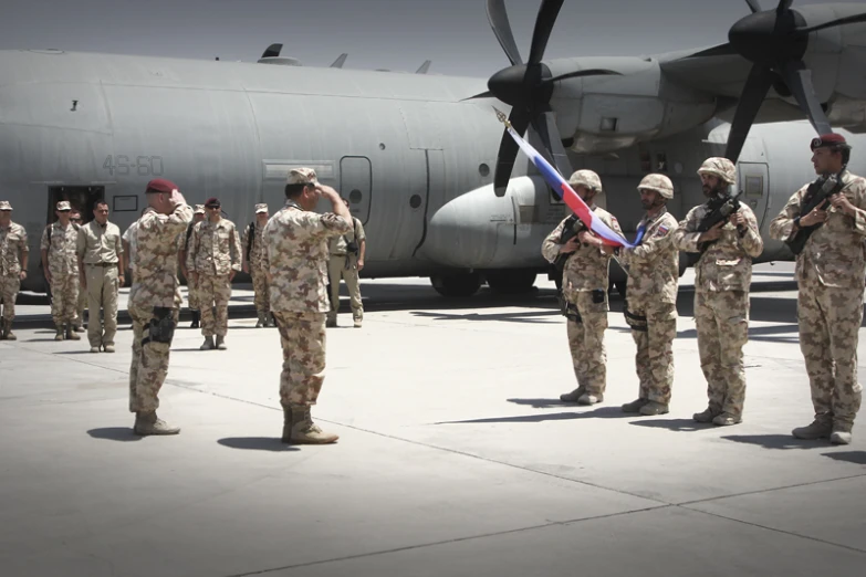 group of soldiers with a flag standing in front of a large aircraft