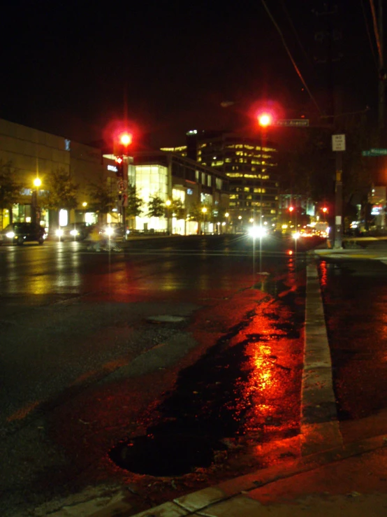 a wet street and some red street lights and buildings