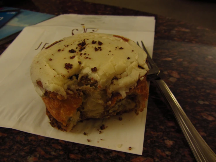 a pastry with vanilla frosting sitting on a napkin