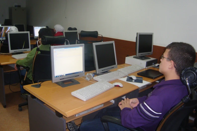 a guy with headphones and earbuds at the computer desk