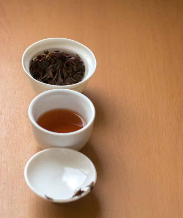 three white bowls with different types of tea in them