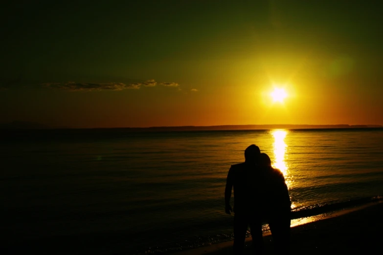 the silhouette of a person standing on a beach as the sun rises