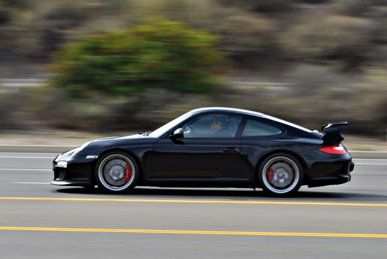 a black porsche is shown driving on the road