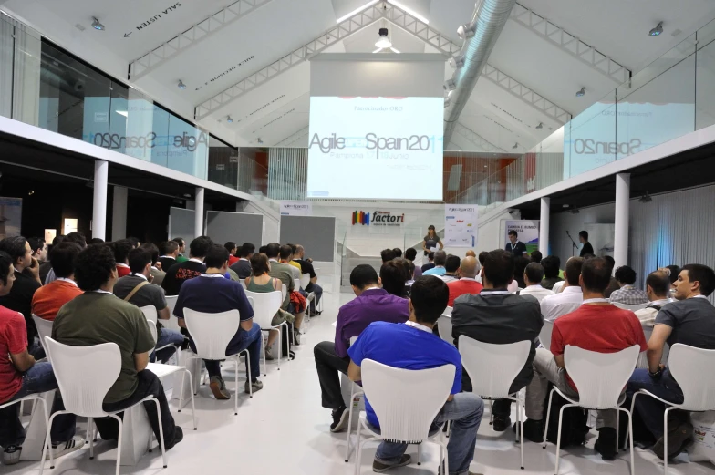 audience listening at presentation in large room with overhead screen