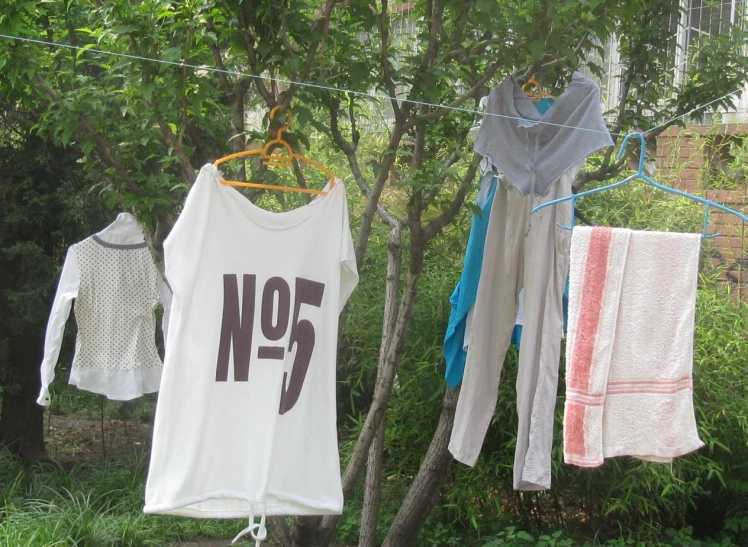 three different shirts hanging from clothesline and one is not