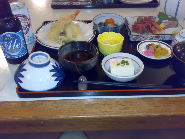 a table with several dishes, two drinks and a tray with food