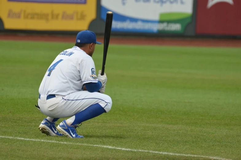 a man that is kneeling down on the ground with a baseball bat