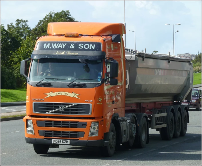 a large orange truck is driving down the road