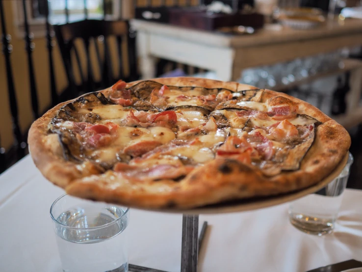 a pizza on a white tablecloth and two glasses