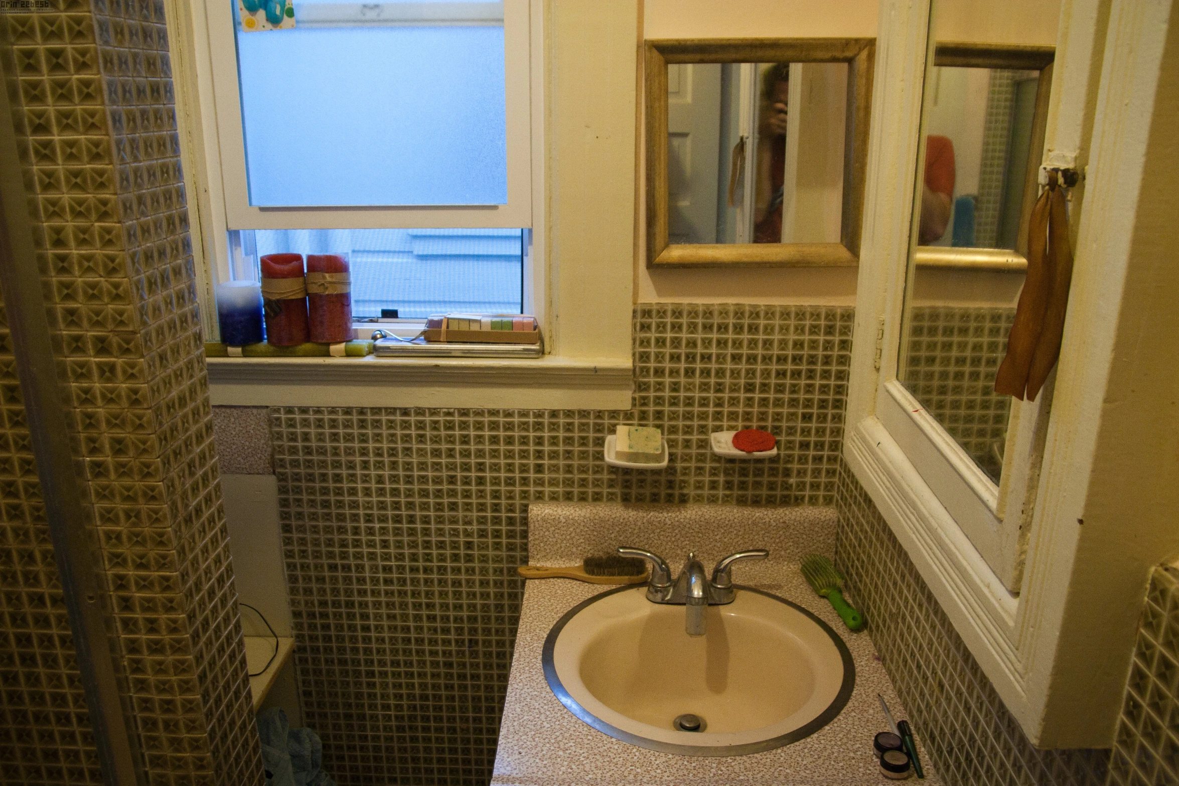 the bathroom sink and mirror is underneath a large window