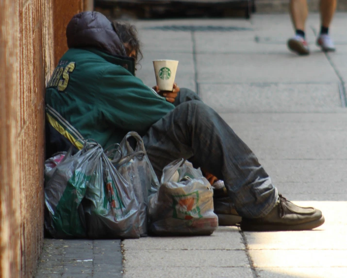 a man sitting against a wall with his legs crossed