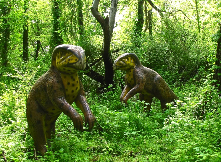 two small dinosaur standing next to each other in the forest