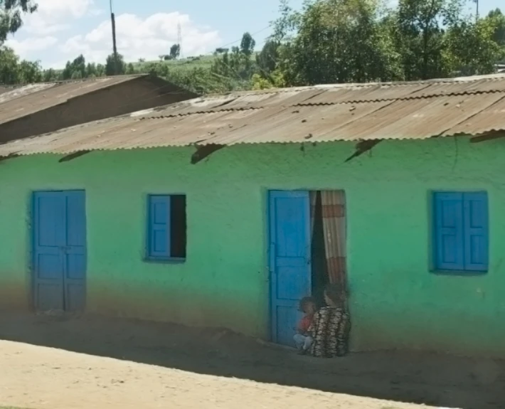 a woman is sitting in front of a green building