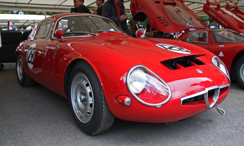 two red classic cars parked next to each other