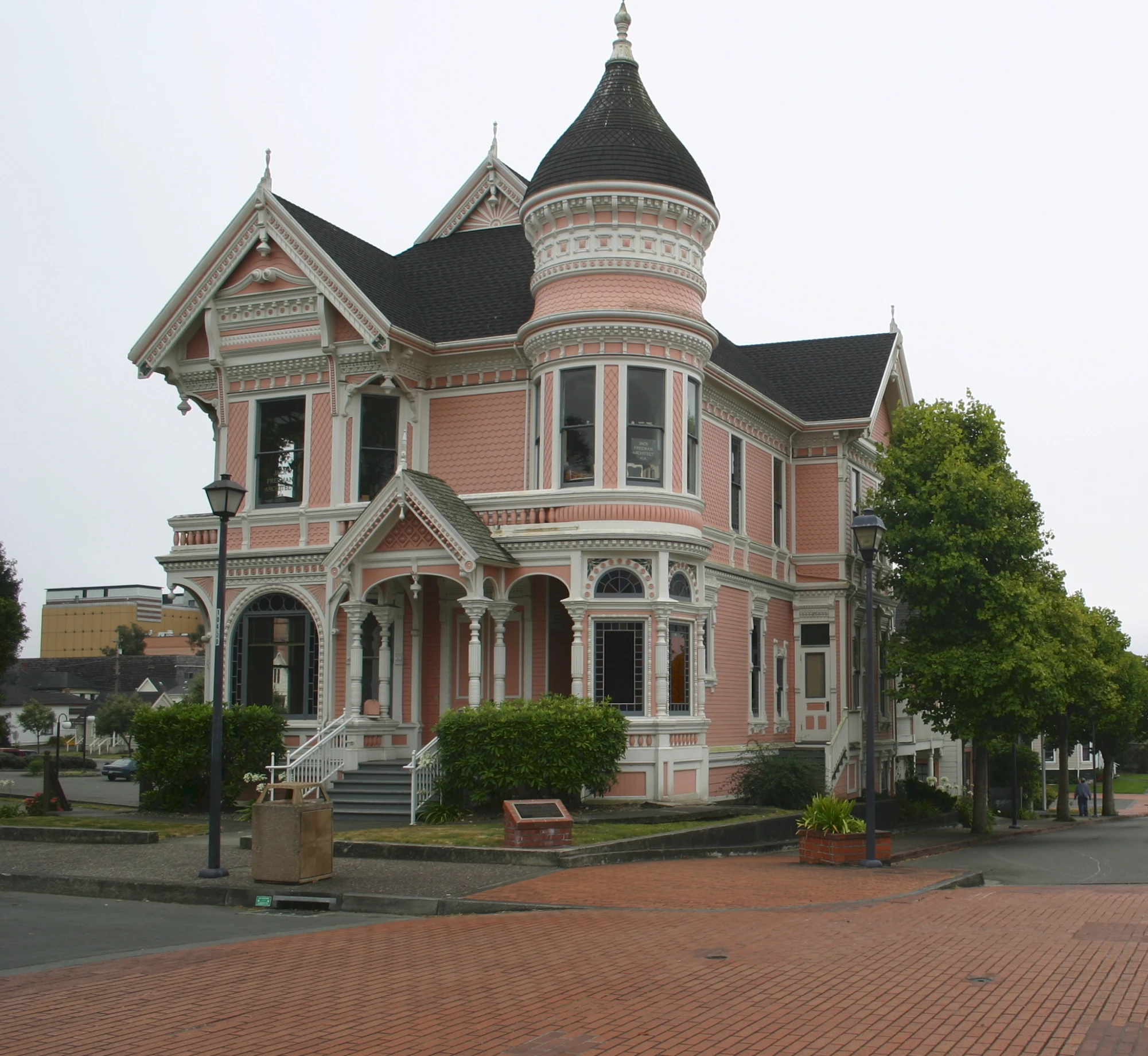 an old pink victorian house on the side of a road