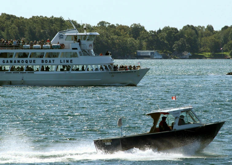 boats travelling in the water in front of a large ferry