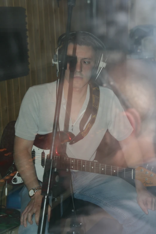a man is sitting in front of a microphone playing a guitar