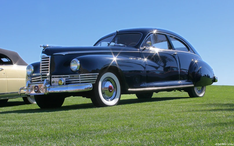 two old fashioned cars are parked on grass