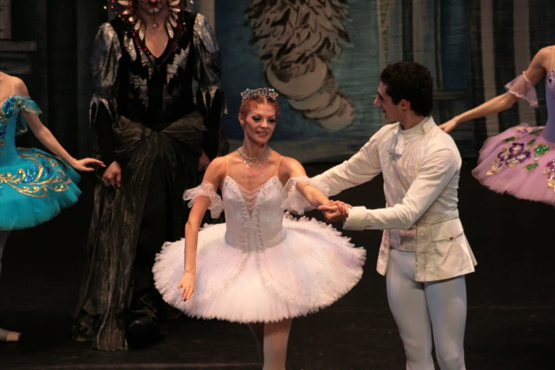 a male dancer holds a female ballet dancer's arm