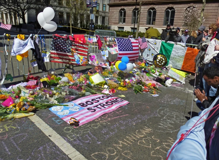 a lot of flowers and balloons laying on a sidewalk