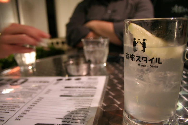 a restaurant menu and drink glass on a bar