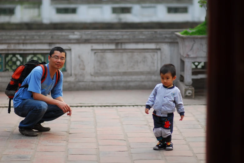 a man kneeling next to a small child