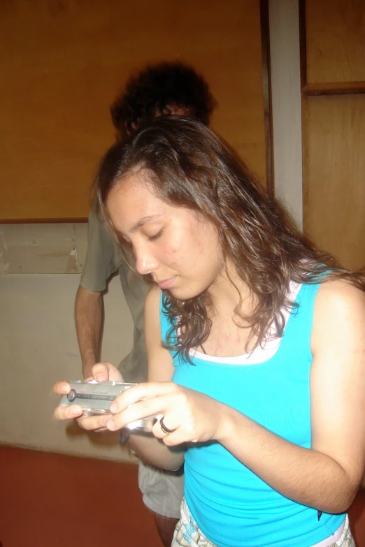 woman in blue shirt looking at cell phone