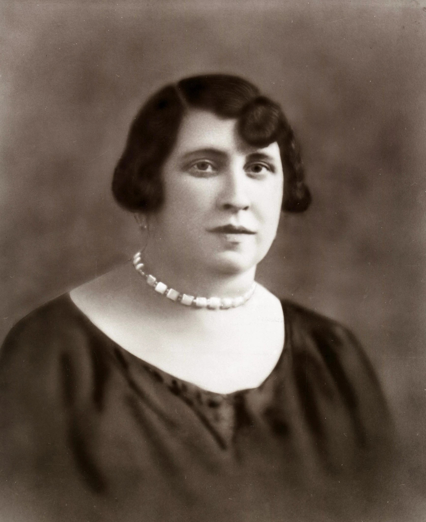 a woman wearing a necklace in an old po