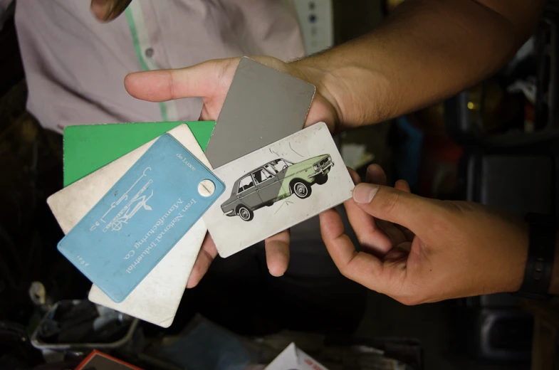 three people hold business cards with cars on them