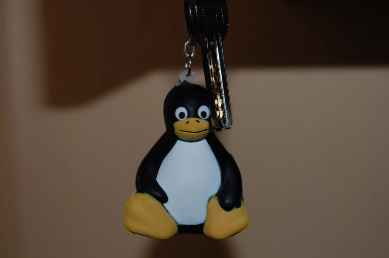 a toy penguin that is laying down on a key chain