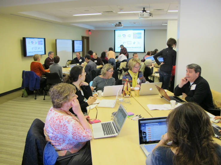 many people are in a boardroom on laptops