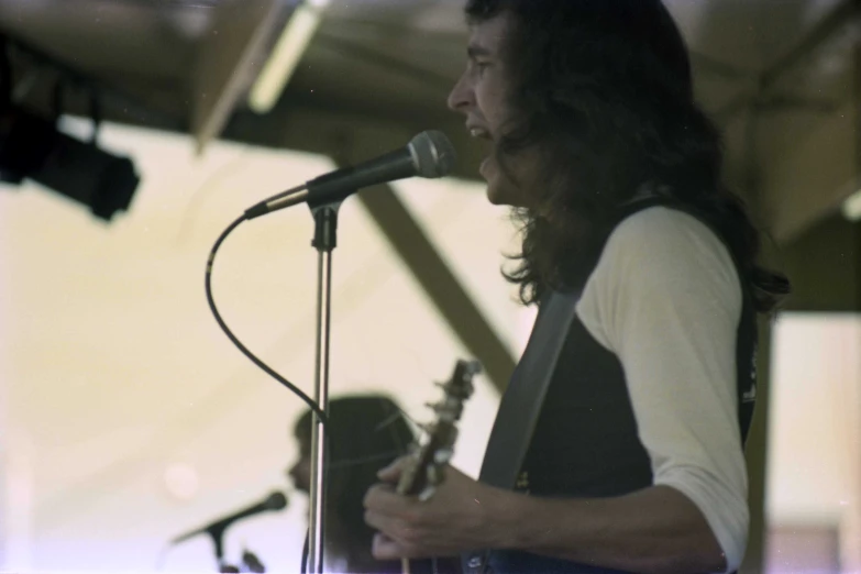 a man playing a guitar and singing into a microphone