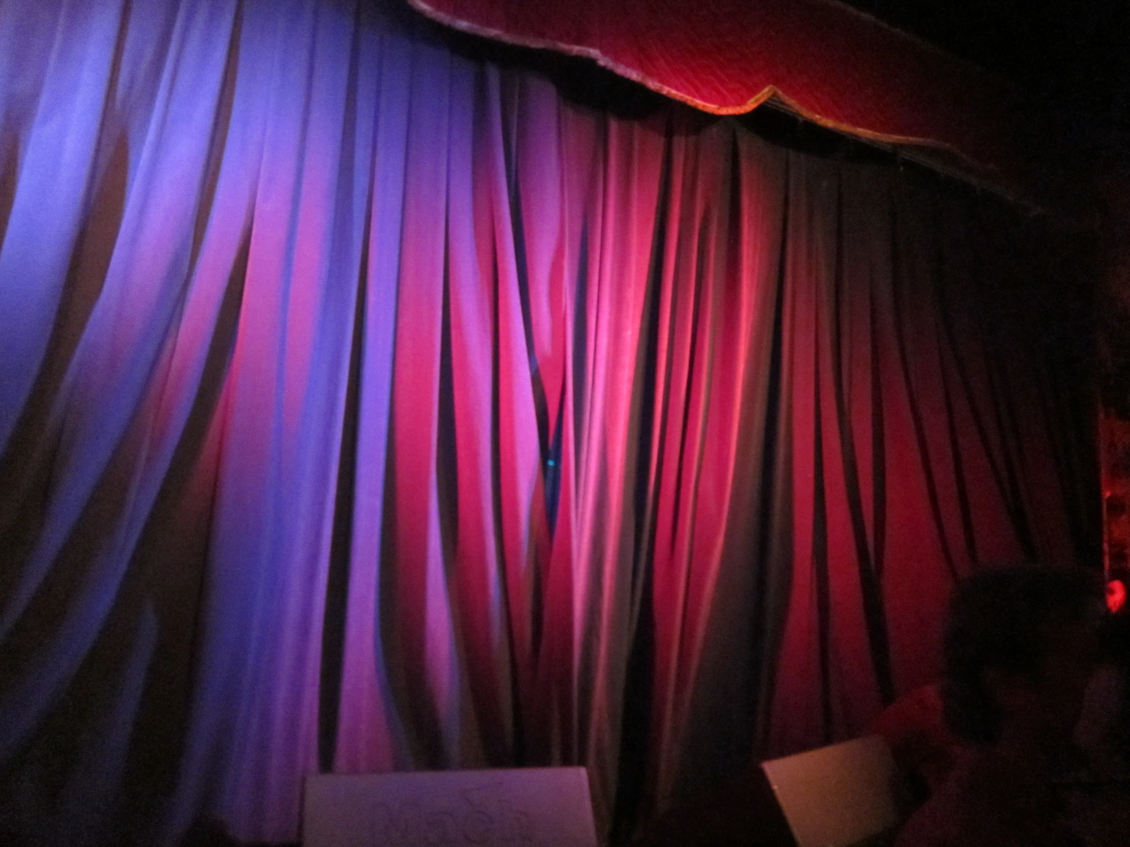 a stage curtain with purple light that appears to be going from the ceiling