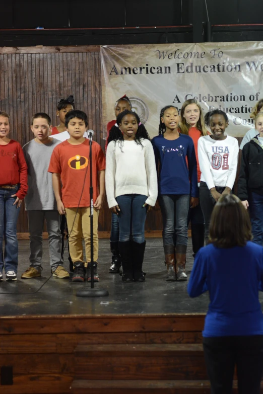 some children standing on stage near a podium