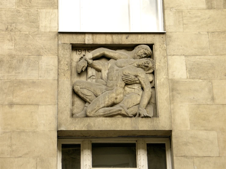 sculpture on side of large building of women fighting