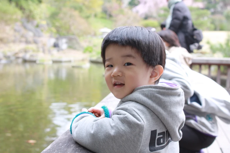 small child leaning on a railing looking at the camera