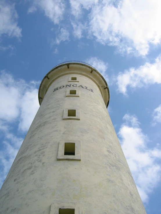 a tall white light house surrounded by clouds