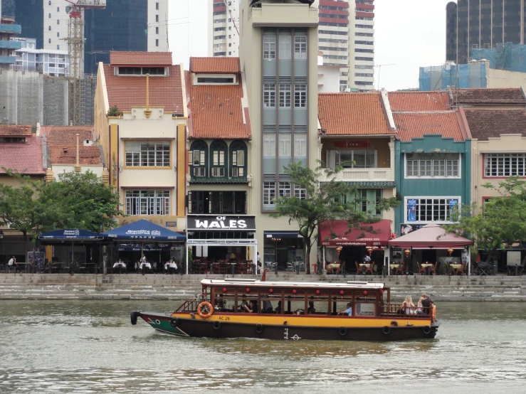 a small houseboat floating down a river near tall buildings