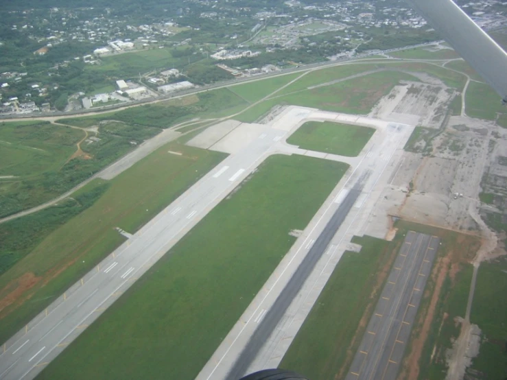 an aerial view of a field of green grass with lots of traffic on the road