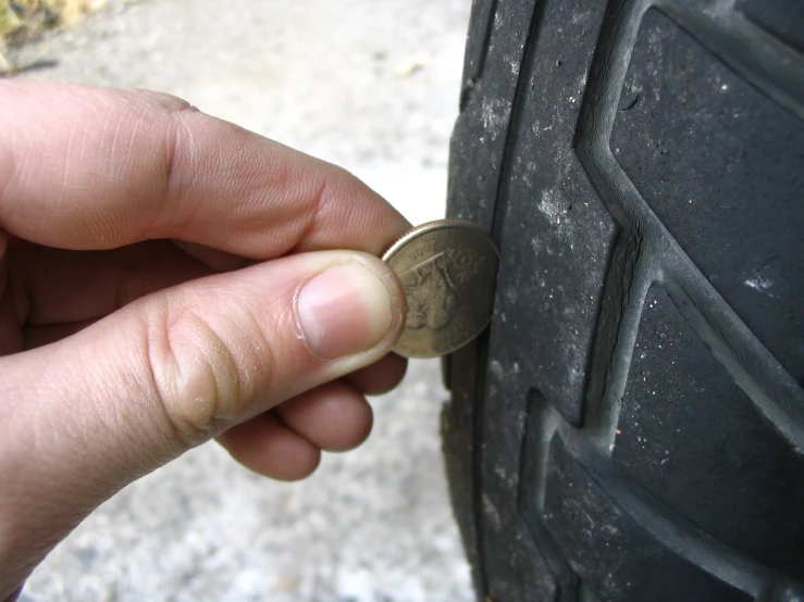 a hand holding a tiny coin and touching it