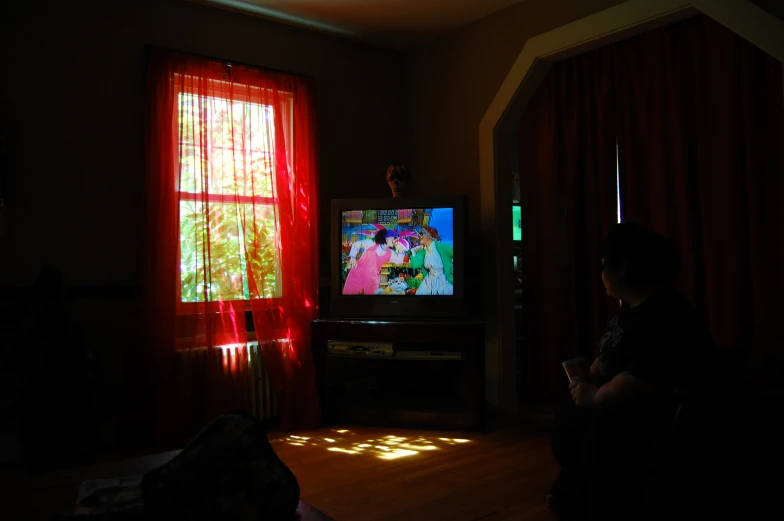 person sitting in front of a tv with red curtains